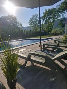 a group of chairs and an umbrella next to a pool at Villa L&M in Bihać