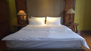 a large bed with white sheets and pillows at Hassan Sisters' EnSuites in Manila