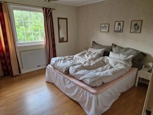 a bed sitting in a room with a window at Hus med stor hage ved Vatsfjorden in Åmsosen
