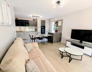 a living room with a couch and a kitchen at T3 neuf Baignots proche Thermes, centre, parking in Dax