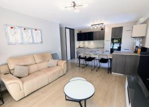 a living room and kitchen with a couch and a table at T3 neuf Baignots proche Thermes, centre, parking in Dax +12 photos