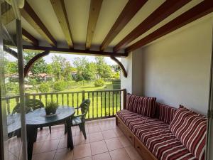 a porch with a couch and a table on a balcony at Appartement de vacance in Uhart-Cize