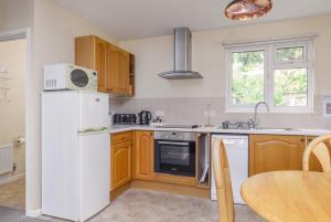a kitchen with a white refrigerator and a table at Sunrise Bay - Mount Brioni in Downderry