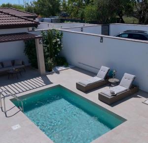 a small swimming pool on a patio with two chairs at Courtyard Villa, Aleksandrovo in Aleksandrovo