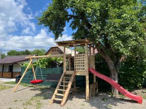 a playground with a tree and a slide at Hill's Peak in Cacica