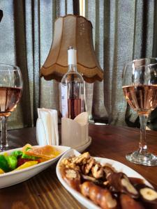 a wooden table with two plates of food and wine glasses at Boutique Hotel Verdzi in Kutaisi