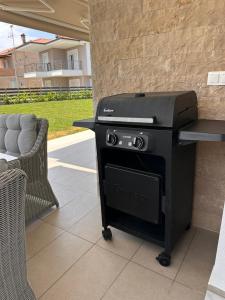 einen Grill auf einer Terrasse neben einem Stuhl in der Unterkunft Royal Apartments - Nikiti in Nikiti