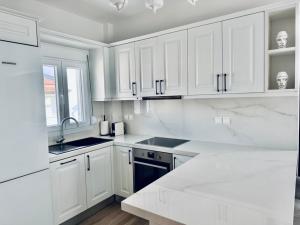 eine weiße Küche mit weißen Schränken und einer Spüle in der Unterkunft Royal Apartments - Nikiti in Nikiti