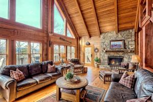 Il comprend un salon doté de meubles et d'une cheminée en pierre. dans l'établissement Secluded Mountain Cabin close to Helen, Georgia, Perfect for a Family Getaway, à Sautee Nacoochee