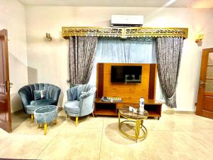 a living room with two chairs and a television at Amada Family Guest House in Karachi
