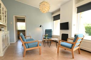 a living room with chairs and a table and a chandelier at Villa Mer - Terra Nova, detached bungalow with XXL garden, near the beach in Cadzand +22 photos