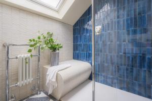 a blue tiled bathroom with a shower with a toilet at Llys y wawr Luxury Holiday Let in Llanfihangel-y-creuddyn +6 photos