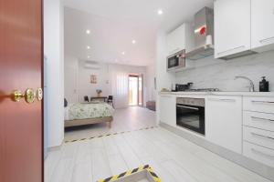 a kitchen with white cabinets and a bed in the background at Attico con balcone - Mare e Comfort in Lido di Ostia