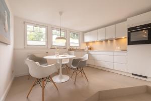 eine weiße Küche mit einem weißen Tisch und Stühlen in der Unterkunft Villa Granitz Wind & Wolke in Ostseebad Sellin