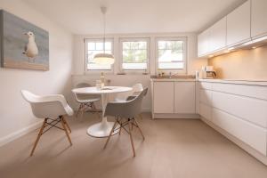 eine Küche mit einem Tisch und weißen Stühlen in der Unterkunft Villa Granitz Wind & Wolke in Ostseebad Sellin + 13 Fotos