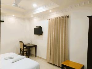 a bedroom with a bed and a table and a television at Hotel Jheel Mahal near City Palace in Udaipur