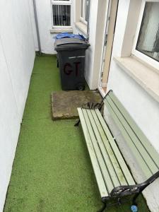 eine Bank neben einem Fenster mit einem Mülleimer in der Unterkunft Glasgow house in Londonderry County Borough