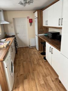 eine Küche mit weißen Schränken und einem Holzboden in der Unterkunft Glasgow house in Londonderry County Borough + 7 Fotos