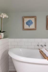 a white bath tub in a bathroom with a picture at The Coach House, Pentland Hills in Nine Mile Burn