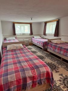 a bedroom with two beds and two windows at Guest House Baiel in Bokonbayevo