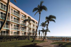 a building with palm trees in front of the ocean at Wyndham Sea Gardens Resort 2BR Apartment with Resort Access in Pompano Beach