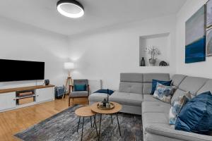a living room with a gray couch and a tv at Hidden Garden , Stylish Stay in Makarska Old Town in Makarska