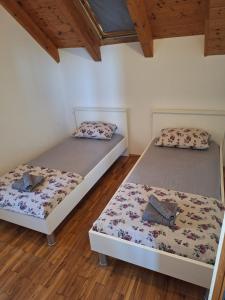 two beds in a room with wooden floors and wooden ceilings at apartman "Dora" in Rogoznica