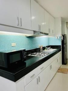 a kitchen with white cabinets and a black microwave at Poolside Condo in Subic Bay in Olongapo