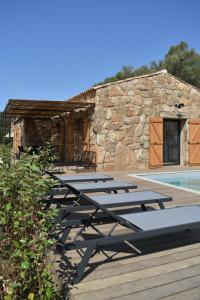 eine Reihe von Chaiselongues auf einem Deck neben einem Gebäude in der Unterkunft Amandula Bergerie Sotta hyper cozy in Sotta