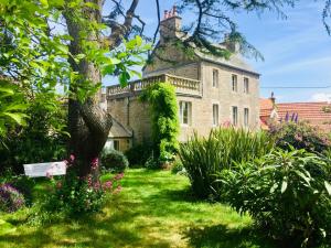 an old stone house with a tree in the yard at Les jardins du Tôt in Fermanville