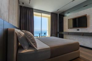 a bedroom with a bed and a tv and a window at Kaiser Resort in Dhërmi
