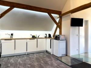 a kitchen with white cabinets and a flat screen tv at Ferienwohnungen Nochten in Nochten