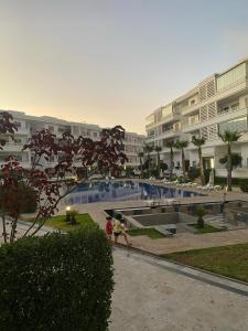 Dos personas caminando junto a una piscina en un edificio. en Apartment in a residence, en Pont Blondin