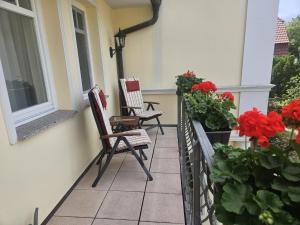 two chairs sitting on a porch with flowers at Villa Viktoria Whg 9 - "Meeresrauschen" in Kölpinsee