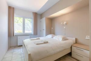 ein Schlafzimmer mit einem großen weißen Bett und einem Fenster in der Unterkunft Huswell - Villa Near Beach with Double Parking in Oostduinkerke