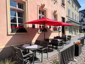 a row of tables and chairs with red umbrellas on a sidewalk at Hotel & Restaurant zum Ritter in Attendorn