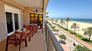 balkon ze stołami i krzesłami oraz widokiem na plażę w obiekcie NEPTUNO GANDIA Primera Línea - Alquiler Familias w mieście Playa de Gandia