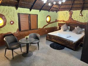 een slaapkamer met een bed, twee stoelen en een tafel bij Ferme hasna in Lubumbashi