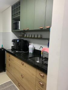 a kitchen counter with a sink and a microwave at Mirantes Garden Residence in Parnamirim +27 photos