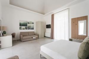 a white bedroom with a bed and a couch at Palazzo Vesuviano in Terzigno