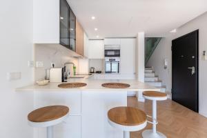 a kitchen with white counters and wooden stools at Vale Do Lobo Resort in Vale do Lobo