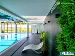 una piscina con un banco en un edificio en Westin House Rodzinny z 2 sypialniami - BASEN, JACUZZI, SAUNA, SALA FITNESS, PLAC ZABAW, PARKING W CENIE - 365PAM, en Kołobrzeg