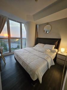 a bedroom with a large bed with a large window at Apartemen Oakwood honolulu in Jakarta