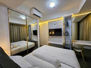 a hotel room with two beds and a tv at Apartemen Oakwood honolulu in Jakarta +4 photos