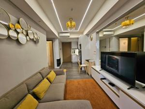 a living room with a couch and a flat screen tv at Apartemen Oakwood honolulu in Jakarta