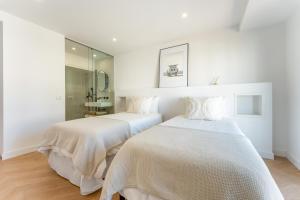 two beds in a white room with a mirror at Vale Do Lobo Resort in Vale do Lobo