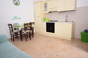 a kitchen with white cabinets and a table and chairs at Bilocale Mancini 4 in Lacona