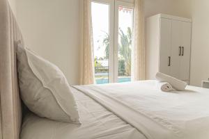 un lit blanc avec un animal rembourré au dessus dans l'établissement Villa Ile d'Eden - Vue mer-Piscine - By Sister Home, à Sainte-Marie 27 autres photos