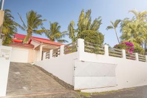 une clôture blanche devant une maison plantée de palmiers dans l'établissement Villa Ile d'Eden - Vue mer-Piscine - By Sister Home, à Sainte-Marie