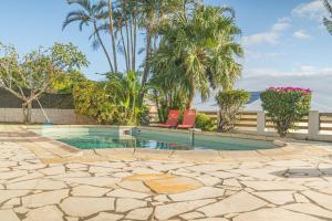 - une piscine avec 2 chaises et des palmiers dans l'établissement Villa Ile d'Eden - Vue mer-Piscine - By Sister Home, à Sainte-Marie